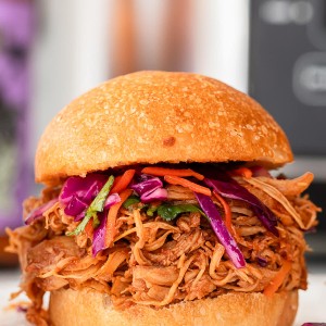 A slow cooker pulled chicken slider with slaw on a white plate.