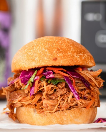 A slow cooker pulled chicken slider with slaw on a white plate.