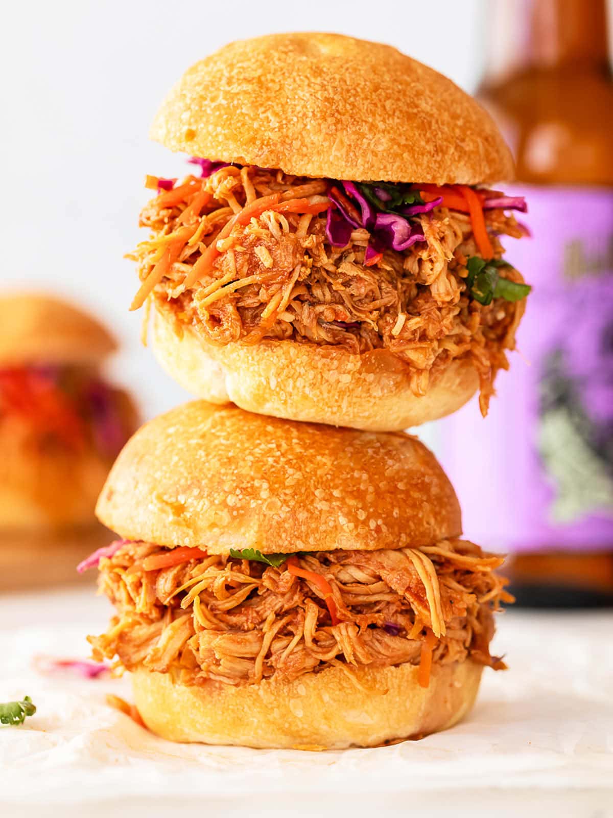 Three Slow Cooker Pulled Chicken sandwiches stacked on top of each other.