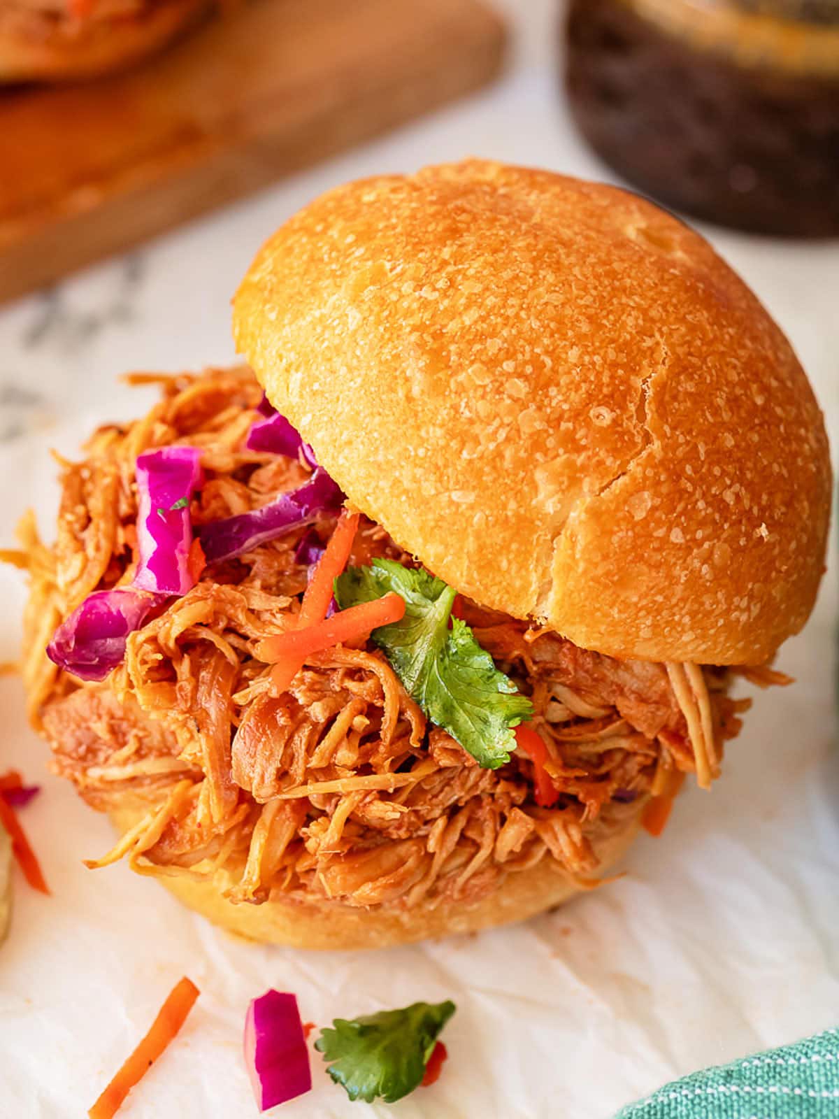A slow cooker pulled chicken sandwich with a side of slaw.