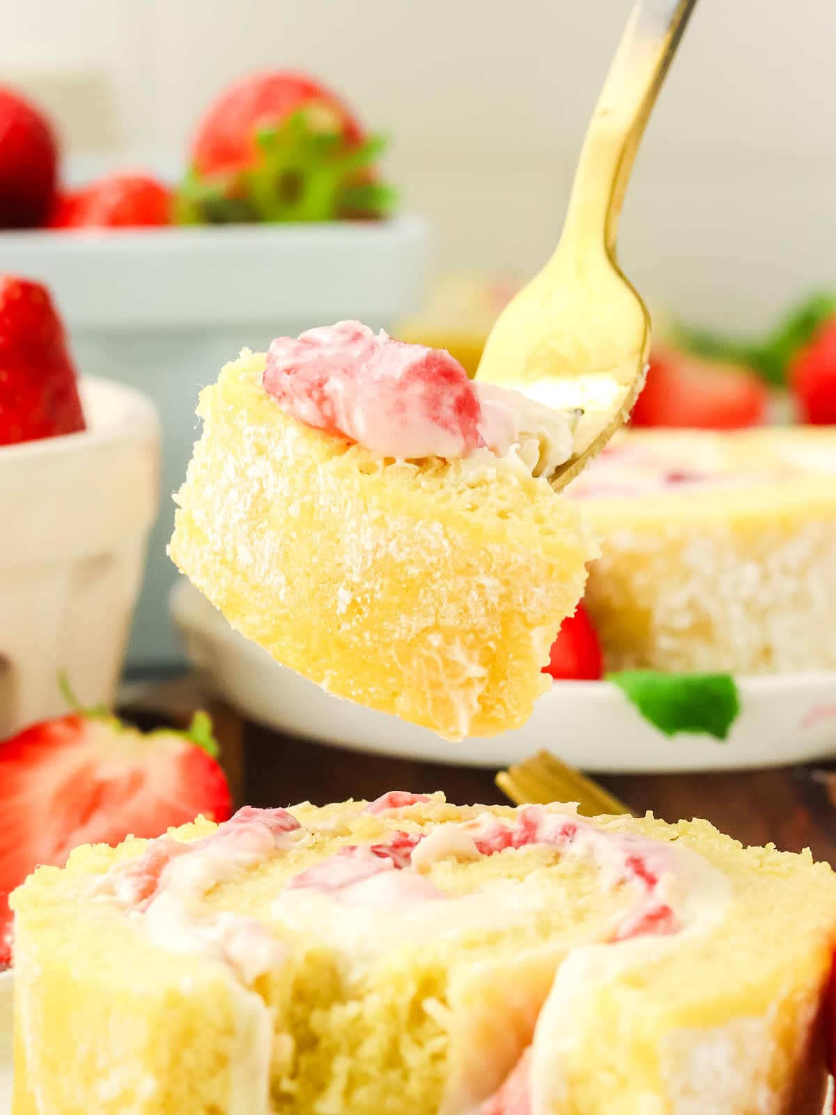 A slice of strawberry roll cake with a spoon.