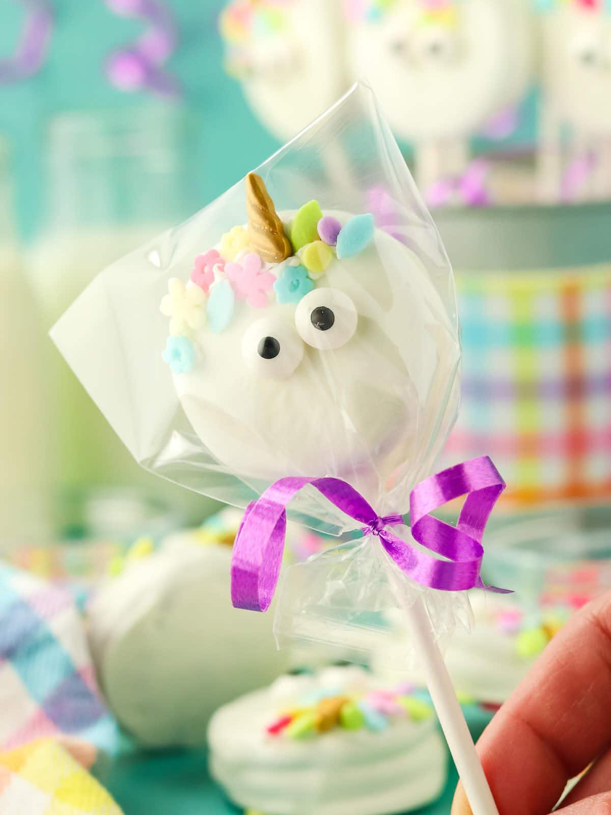 A person is holding a unicorn lollipop on a stick.