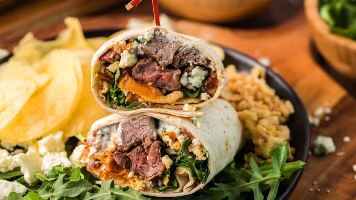 A burrito with meat and vegetables on a plate.