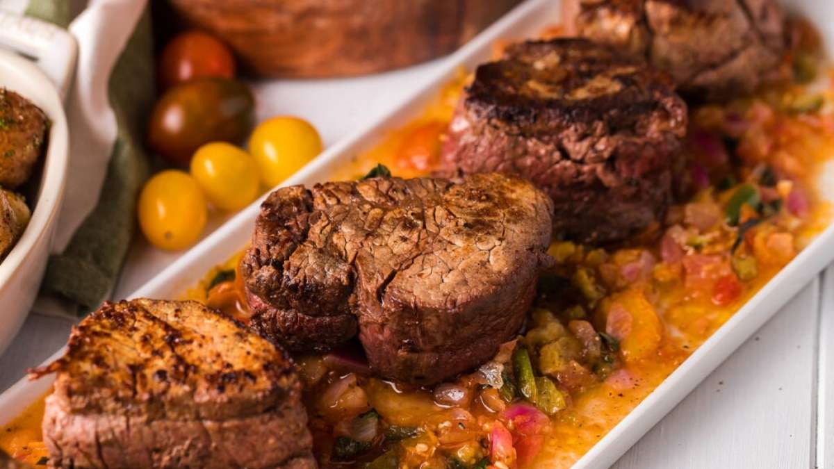 Beef tenderloin with tomato sauce on a white plate.
