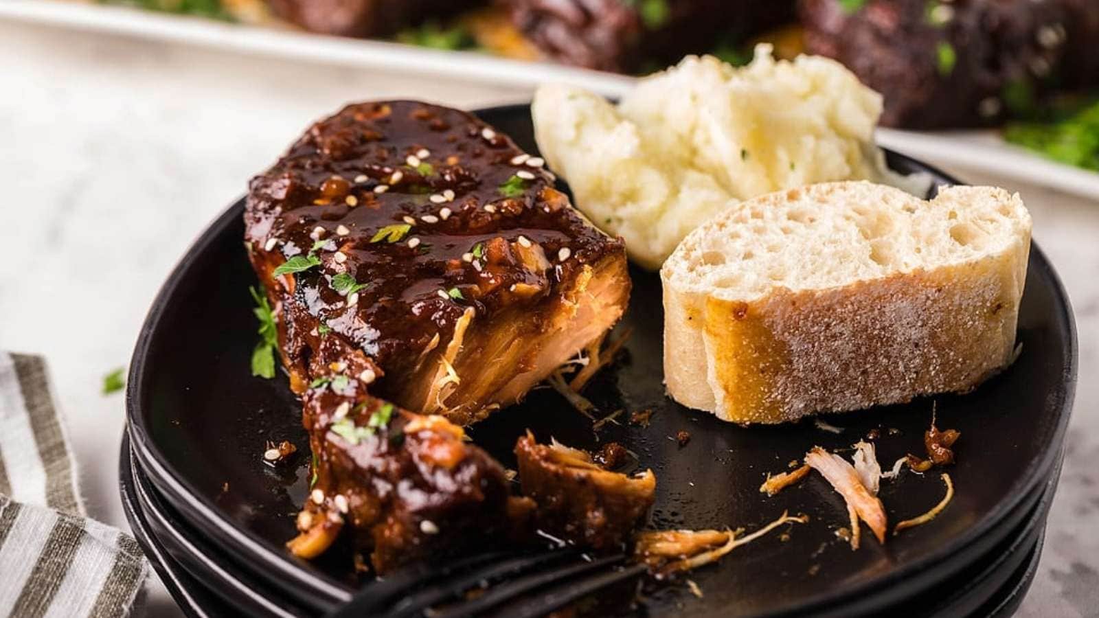 Bbq ribs on a black plate with bread.