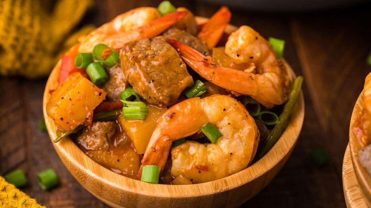 A bowl of shrimp and vegetables on a wooden table.