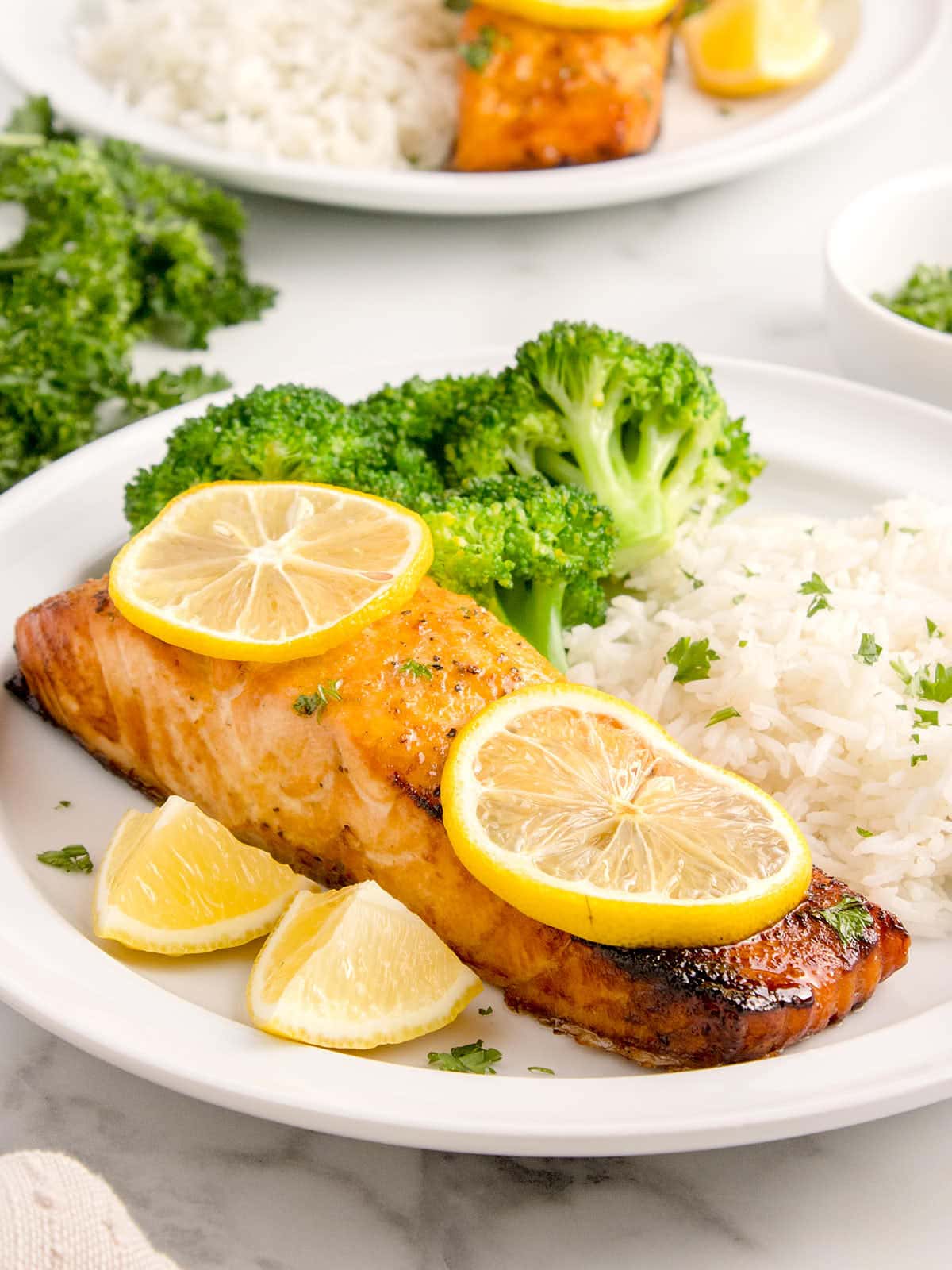 Air Fryer Lemon Pepper Salmon served on a white plate with rice and broccoli.
