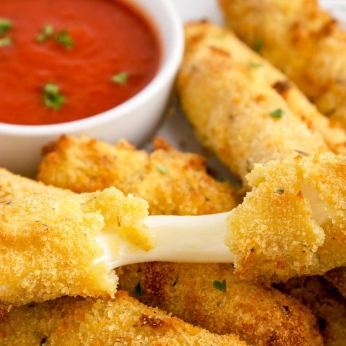 Air Fryer Mozzarella Sticks served on a white plate with marinara sauce.
