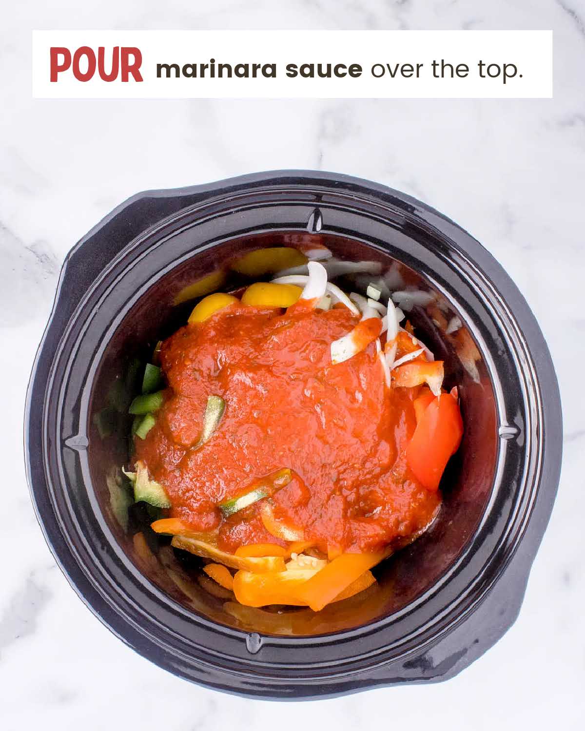 Sliced onions and bell peppers covered with marinara sauce in a crockpot.