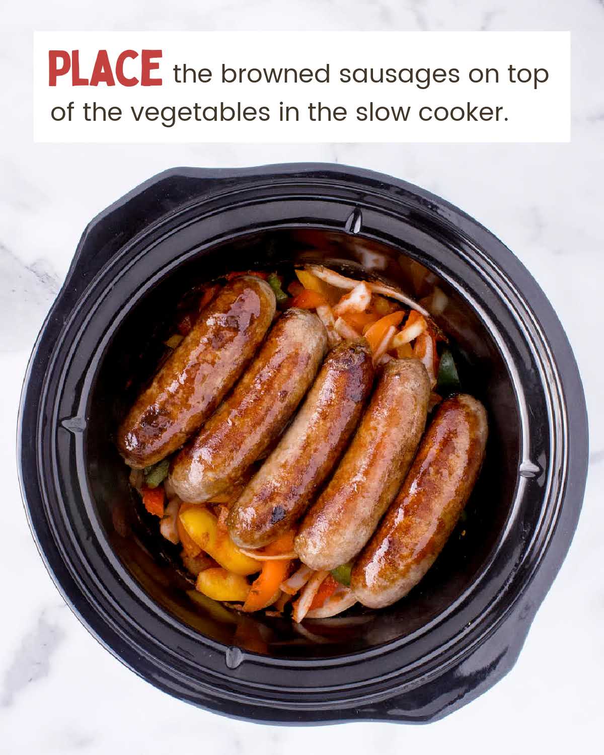 Browned sausages on top of peppers and onions in a crockpot.