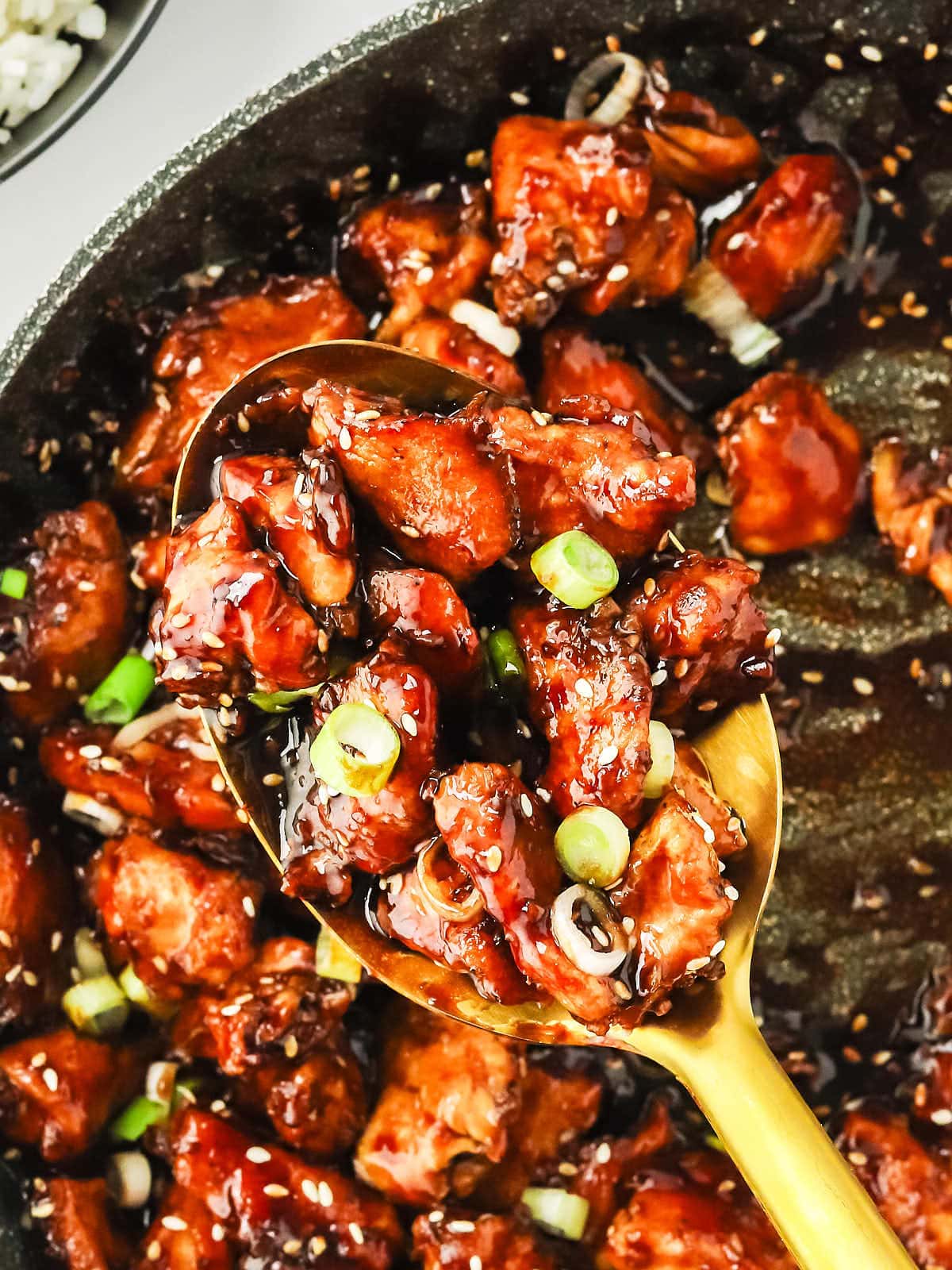 Closeup of large serving spoon filled with Sesame Chicken.