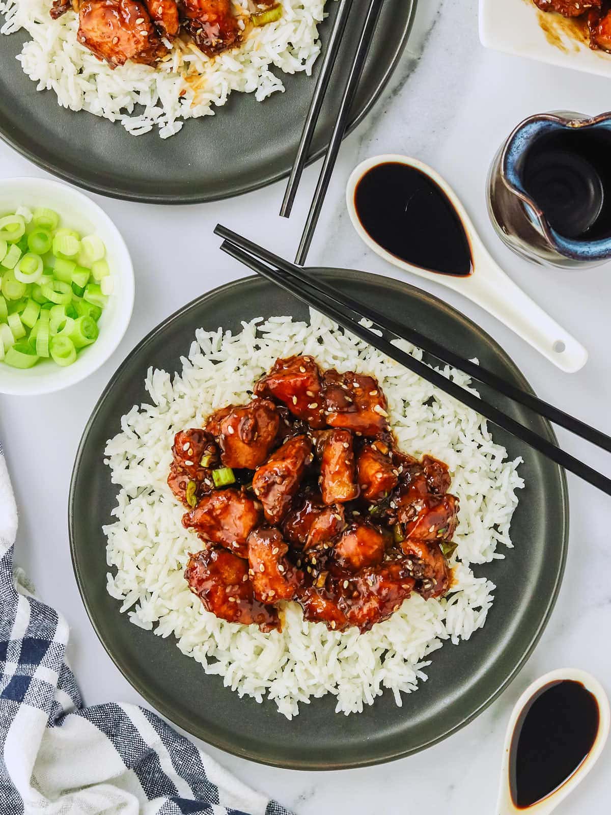 Sesame Chicken served over rice on a black plate.