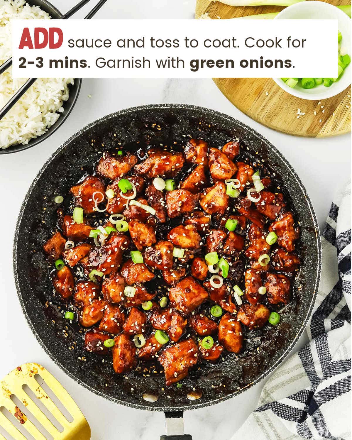 Sesame chicken in a pan garnished with green onions.
