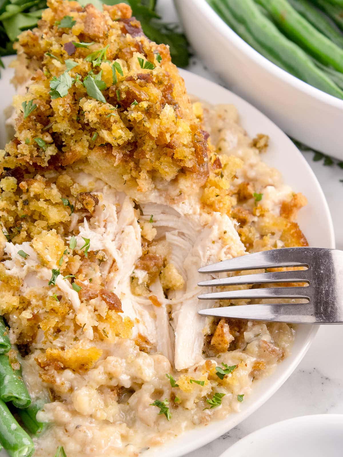 Crockpot Chicken and Stuffing on a white plate served with green beans.