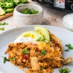 Chicken Enchilada Casserole on a plate with a Crock Pot in the background.