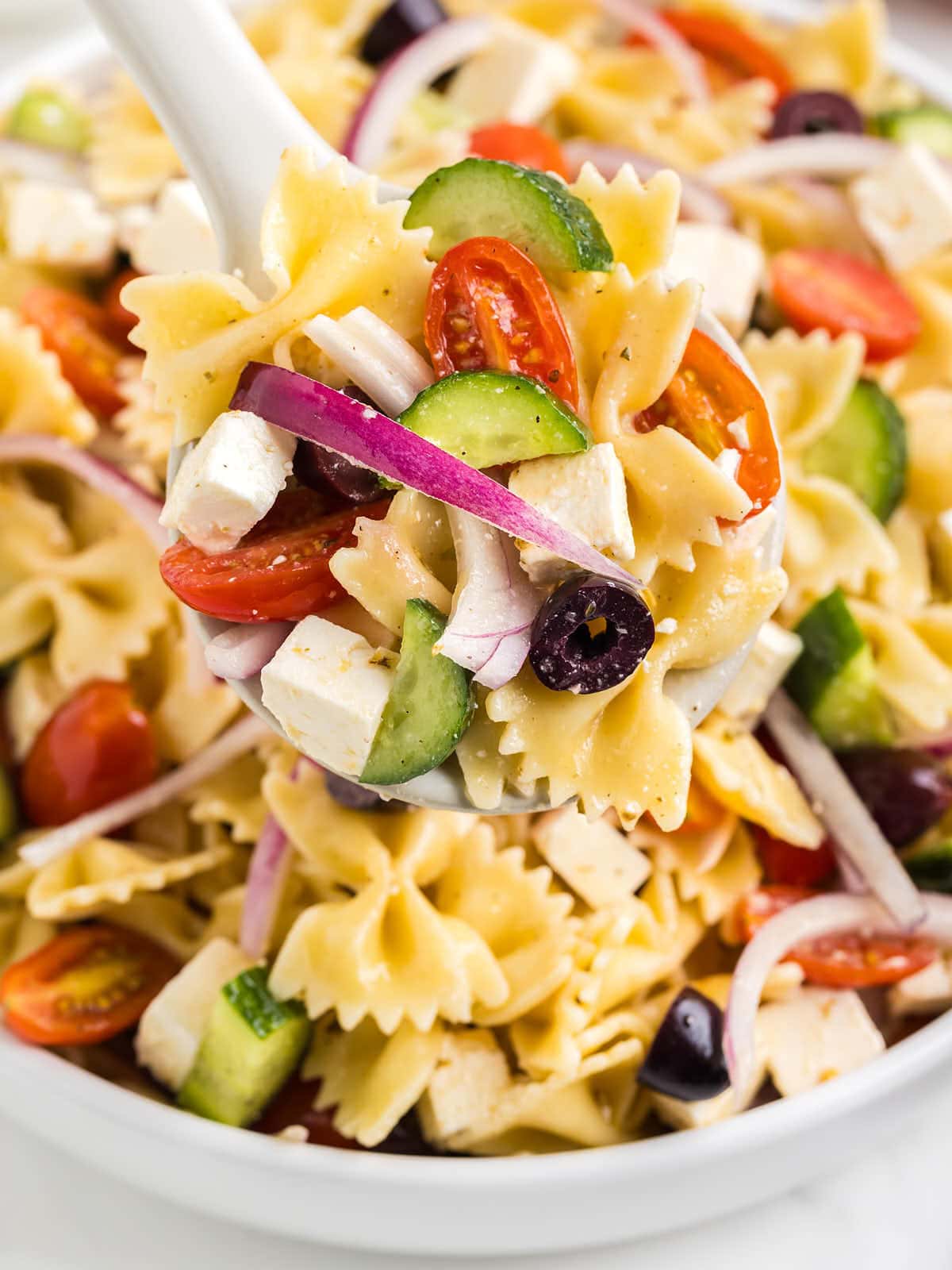 Closeup of a serving spoon filled with Greek Pasta Salad.