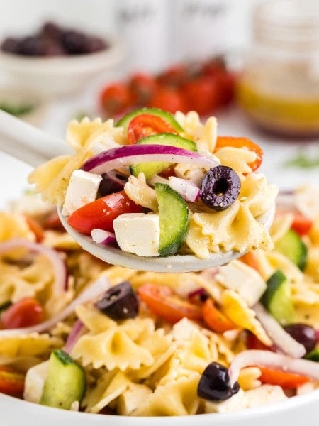 Closeup of a serving spoon filled with freshly made Greek Pasta Salad.