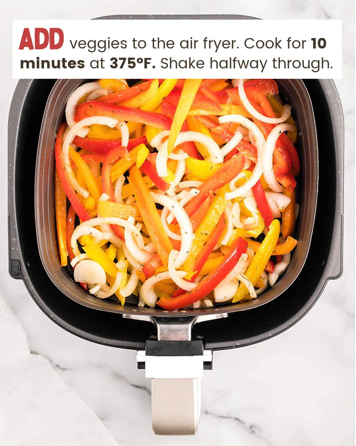 Adding veggies to air fryer for Air Fryer Chicken Sausage and Peppers.