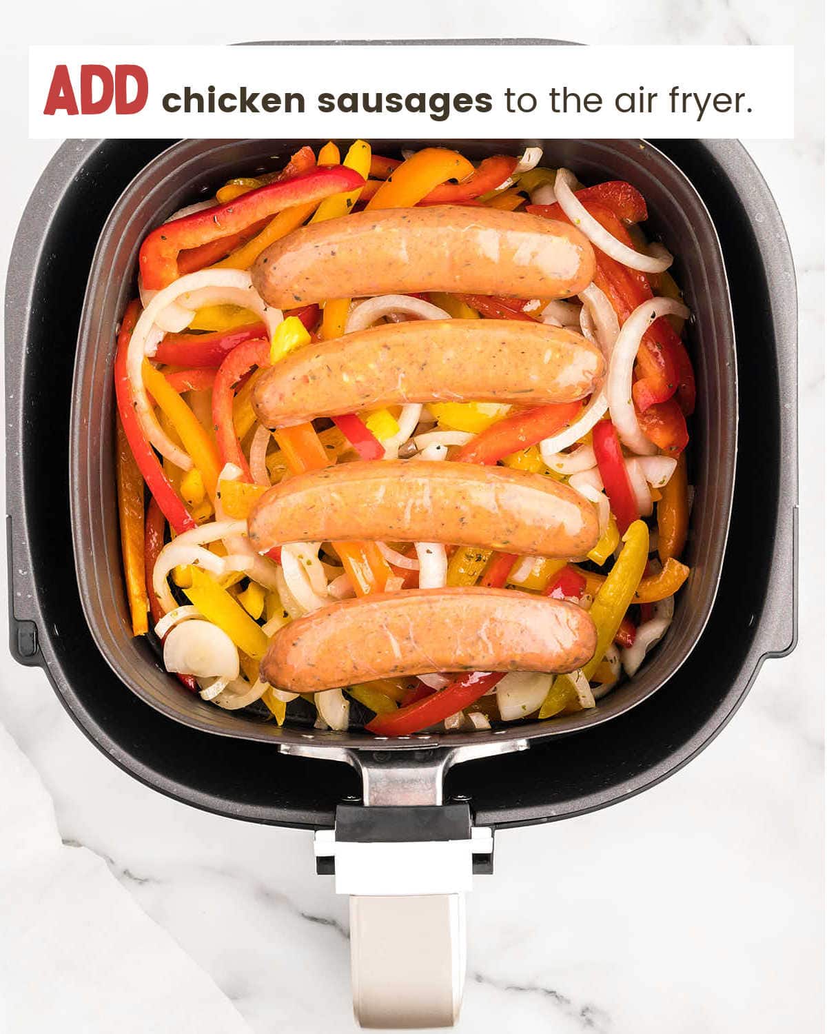 Adding sausage to air fryer for Air Fryer Chicken Sausage and Peppers.