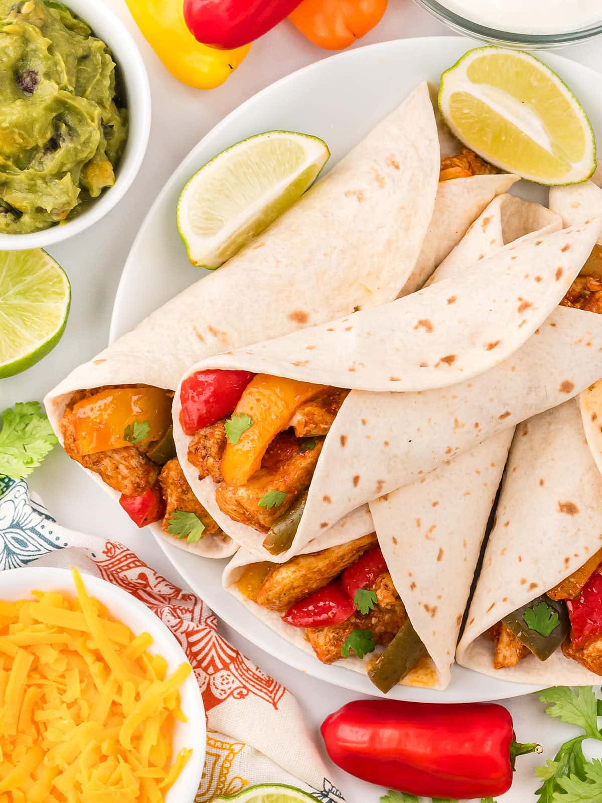 Crockpot Chicken Fajitas served in soft taco wraps on a white plate.
