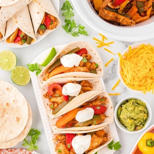 Top down view of Crockpot Chicken Fajitas served in soft taco wraps with all the toppings.