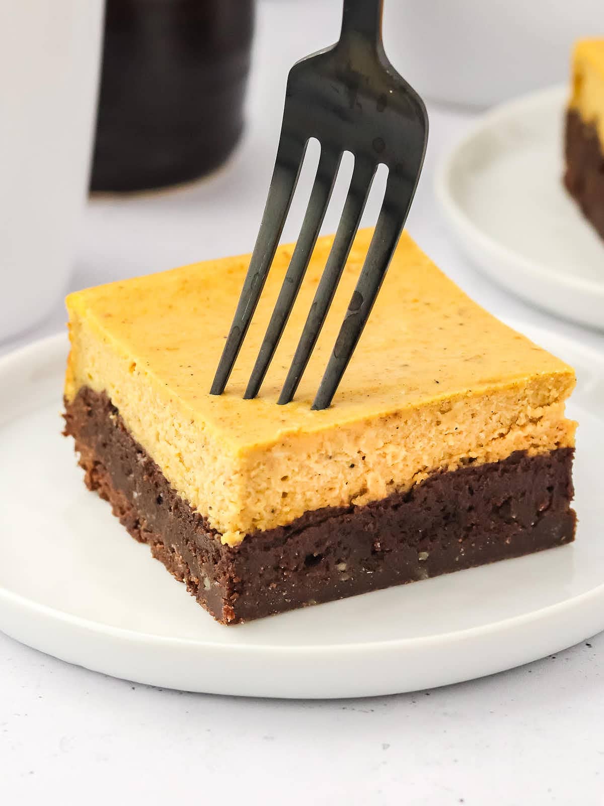 A slice of Pumpkin Cheesecake Brownies on a a white plate.