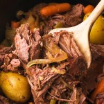 A wooden spoon removing cooked Slow Cooker Sirloin Tip Roast.