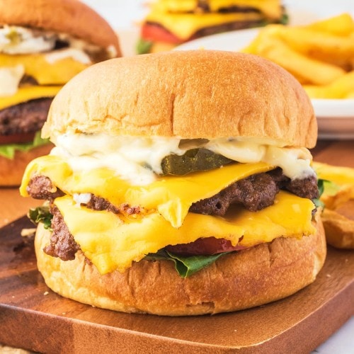 Closeup of a Smash Burger on a wooden plate.