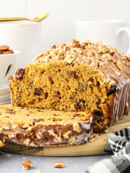 A loaf of Sweet Potato Bread topped with a glazed and drizzled with chopped pecans.