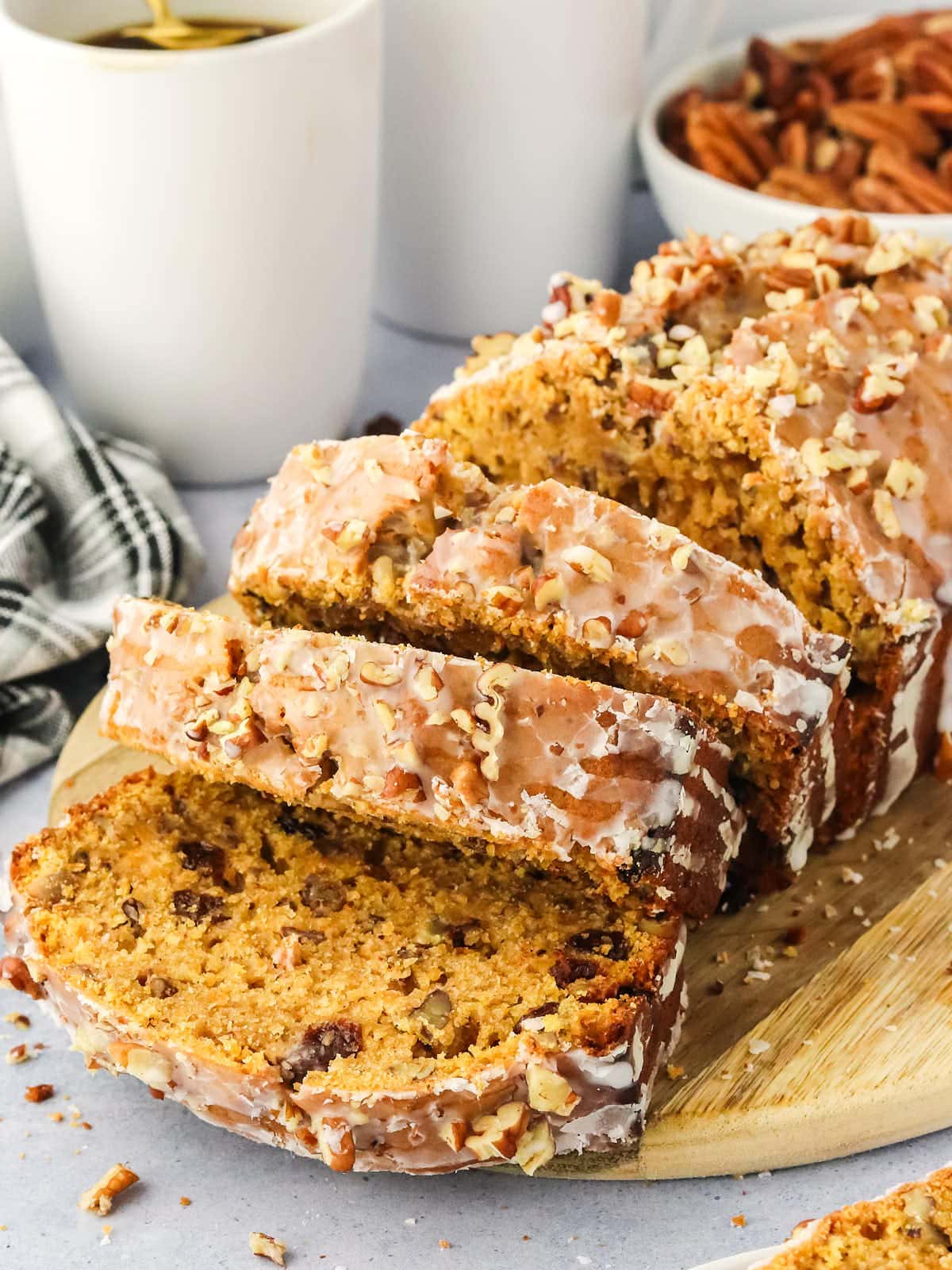 A loaf of Sweet Potato Bread topped with a glazed and drizzled with chopped pecans.