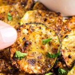 Holding up a slice of air-fried Zucchini Chips.