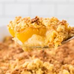 A serving spoon filled with Peach Cobbler Dump Cake.