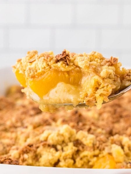 A serving spoon filled with Peach Cobbler Dump Cake.