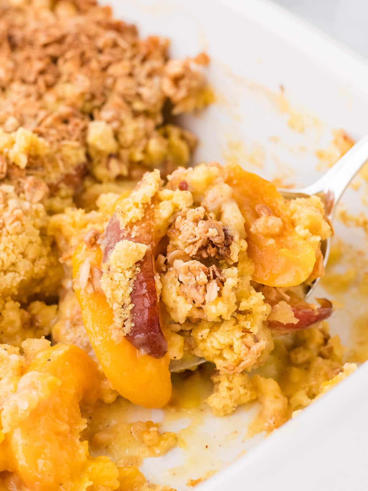 Spooning out a Peach Cobbler Dump Cake out of a casserole dish.