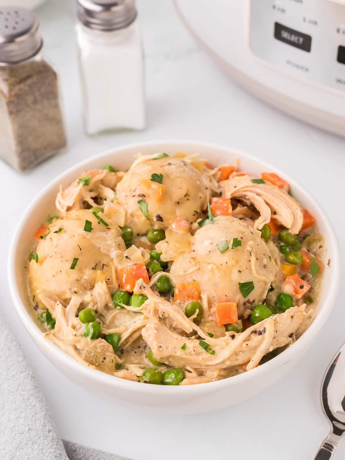 Chicken and Dumplings made in a Crockpot served in a white bowl.