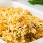 Tuna Casserole being served in a white casserole dish with a serving spoon.