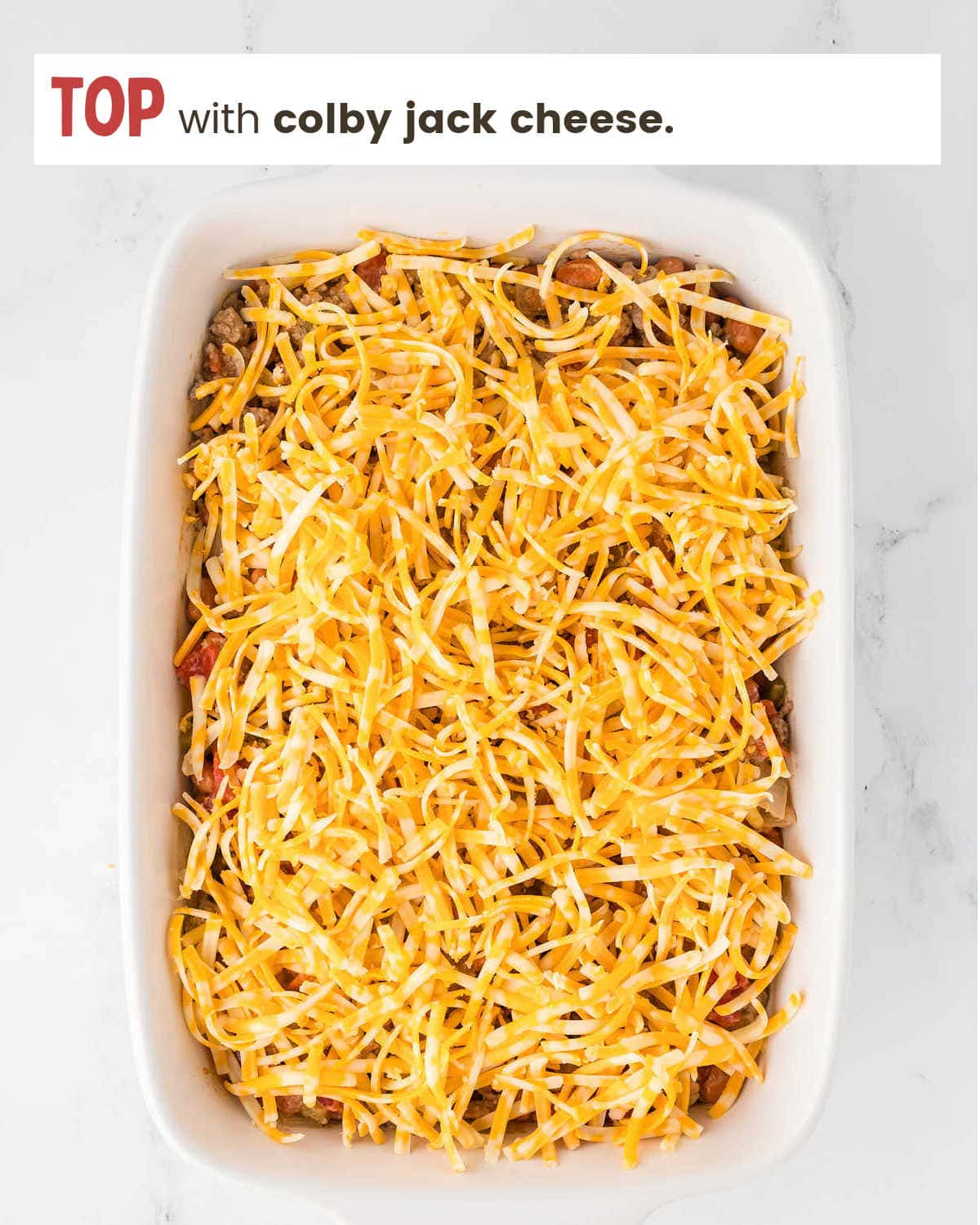 Topping beef mixtures with shredded cheese for Walking Taco Casserole.