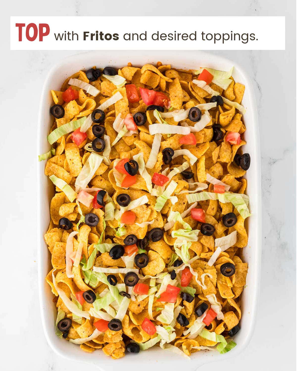 Topping Walking Taco Casserole with corn chips and veggies.