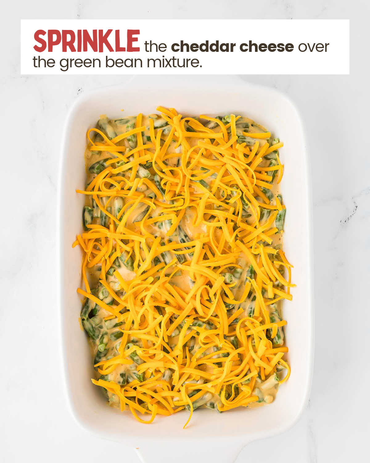 Cheddar cheese on top of green bean casserole in a casserole dish.