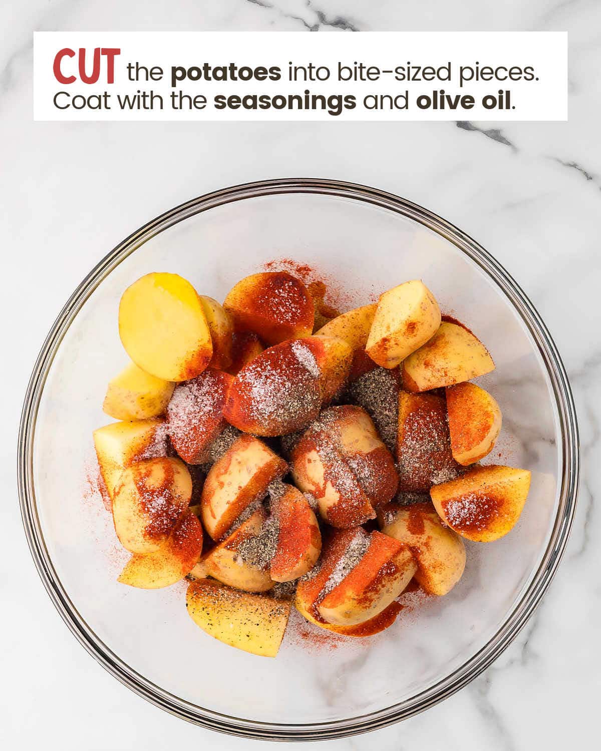 Potatoes in a bowl topped with seasonings.