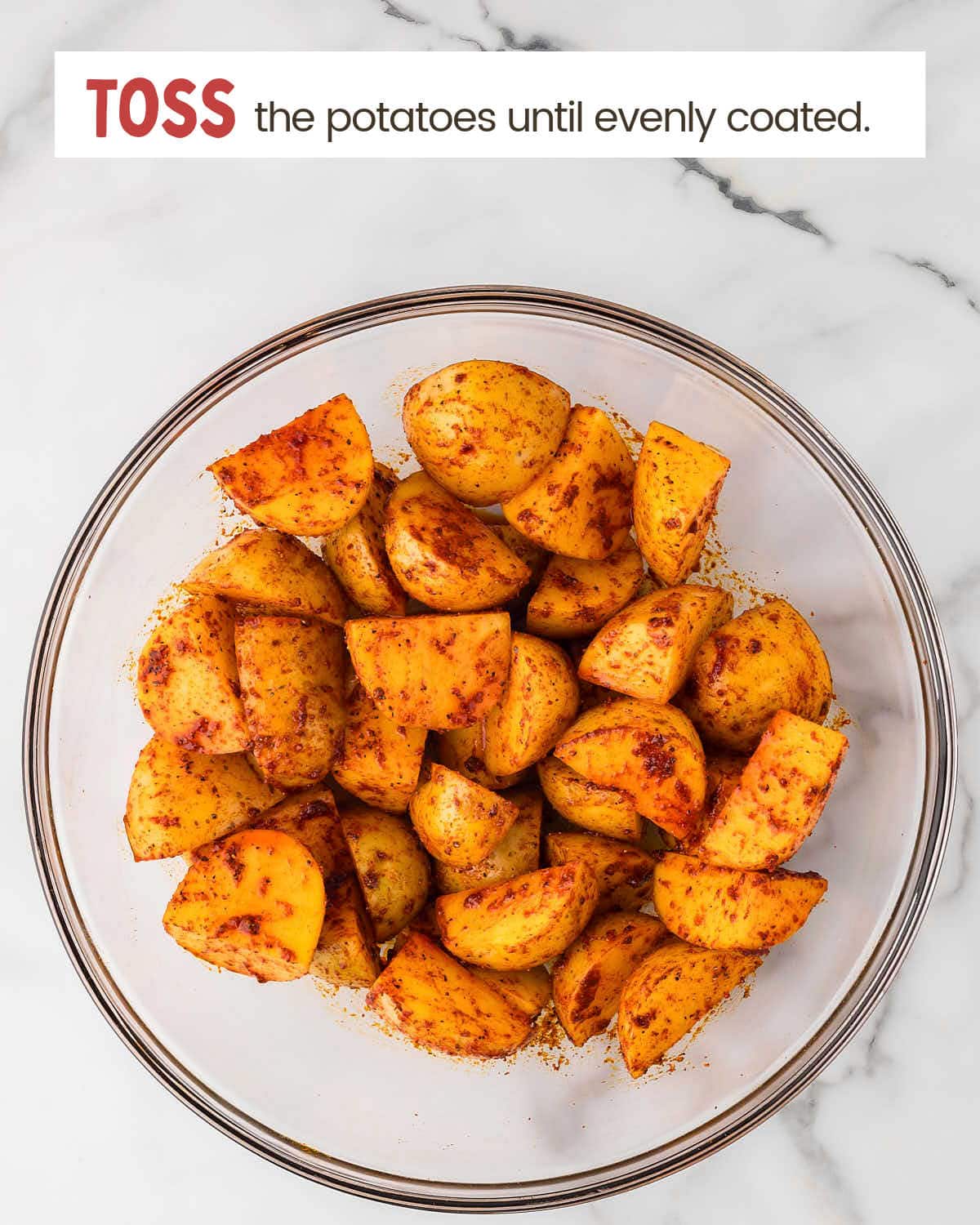 Potatoes in a bowl coated with seasonings.