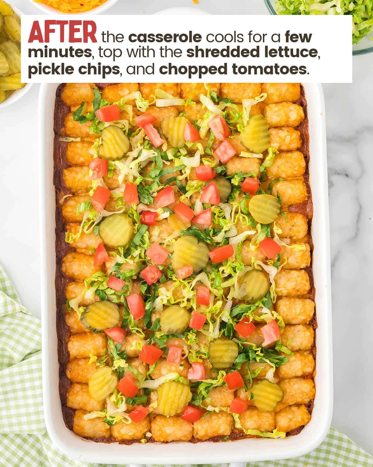 Big Mac tater tot casserole in a dish topped with lettuce, tomatoes, and pickle chips.