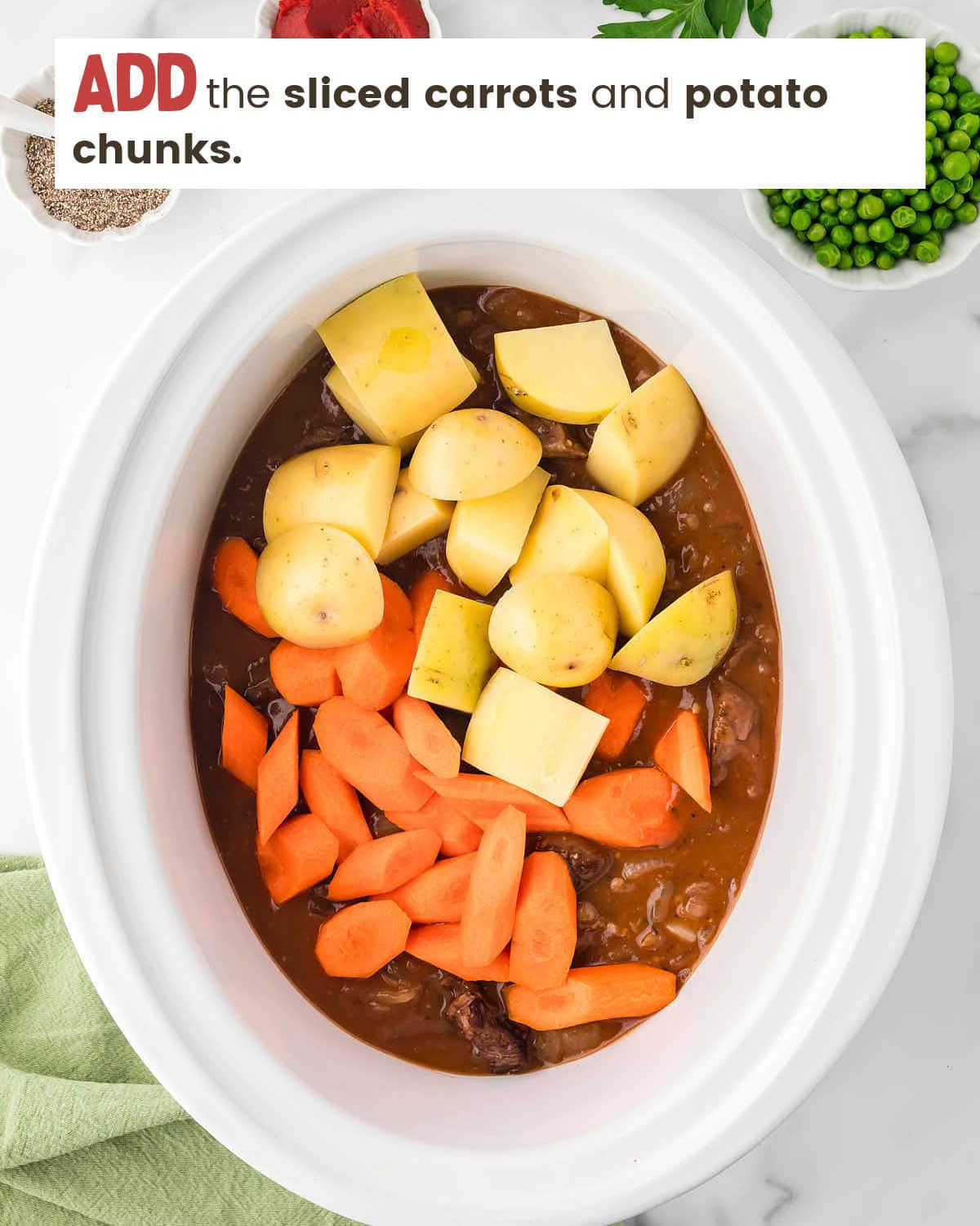 Carrots and potatoes are added on top of other ingredients for beef stew in a slow cooker.