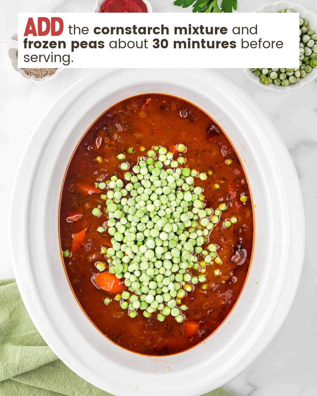 Frozen peas are added on top of beef stew in a slow cooker.