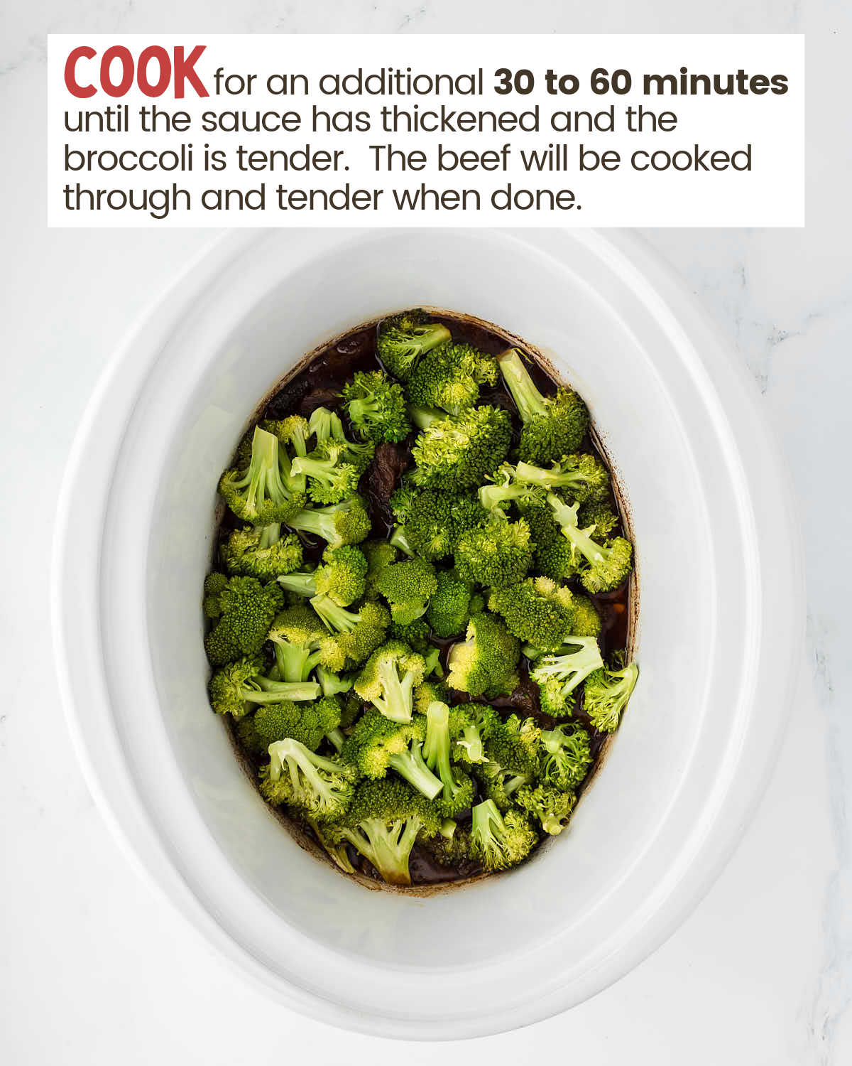 Broccoli covers beef and sauce in a slow cooker.
