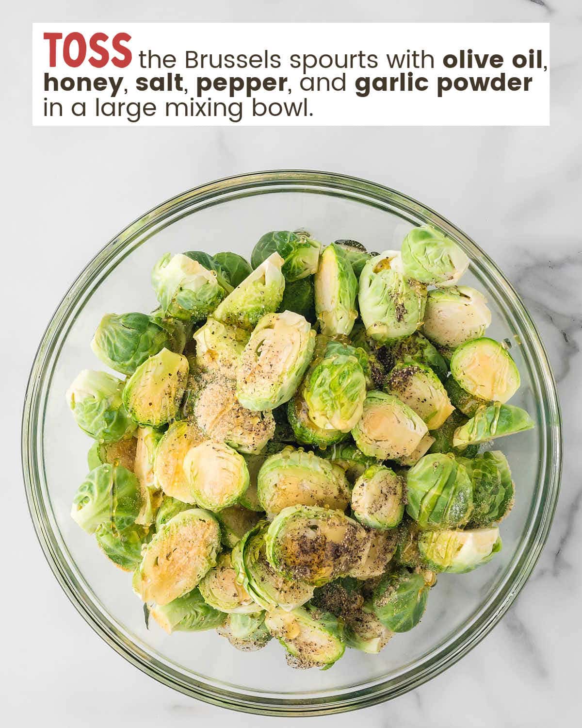 Brussels sprouts in a mixing bowl with text instructions to toss them with honey and spices.