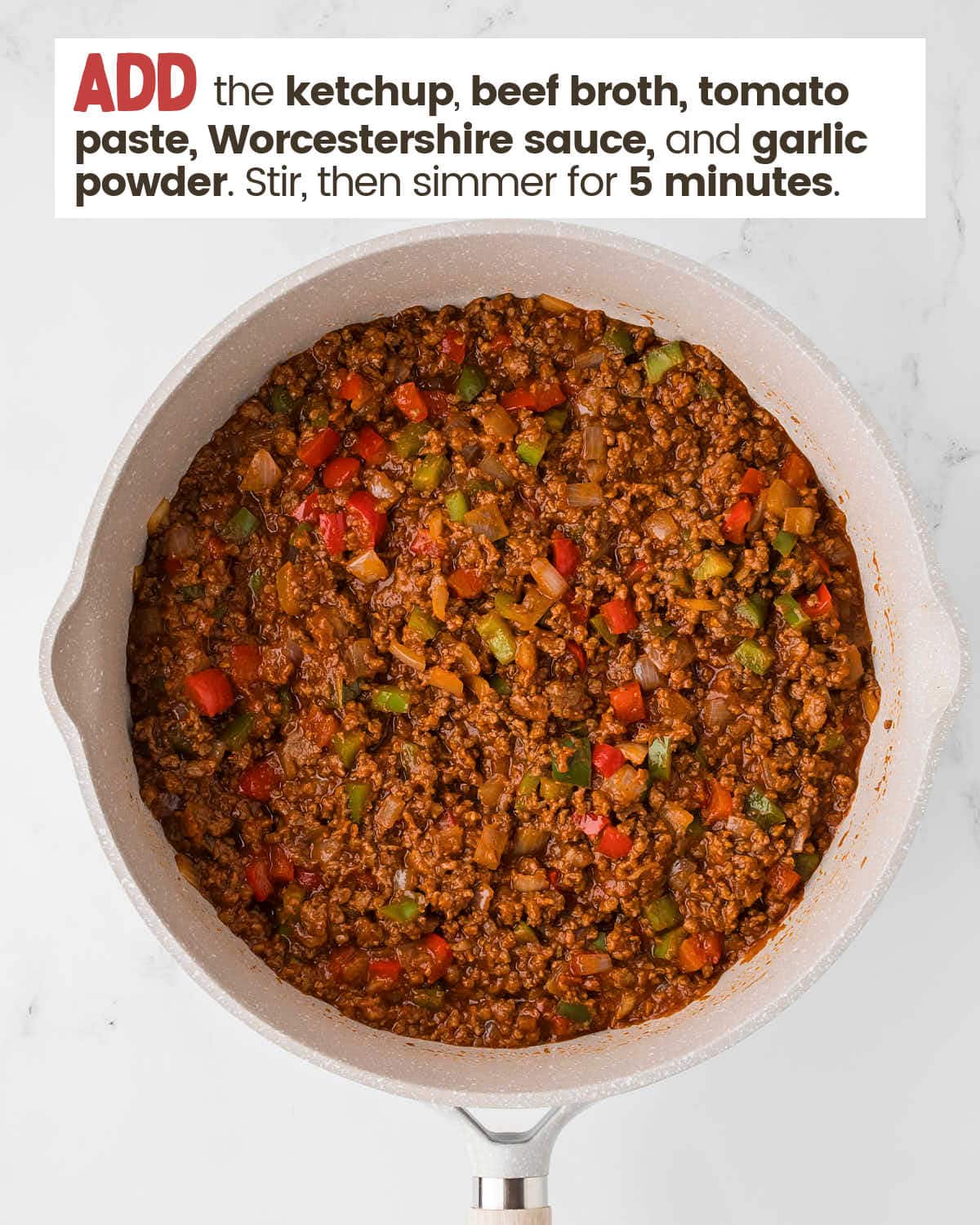 Browned beef with sauce, onions, and peppers in a large skillet.