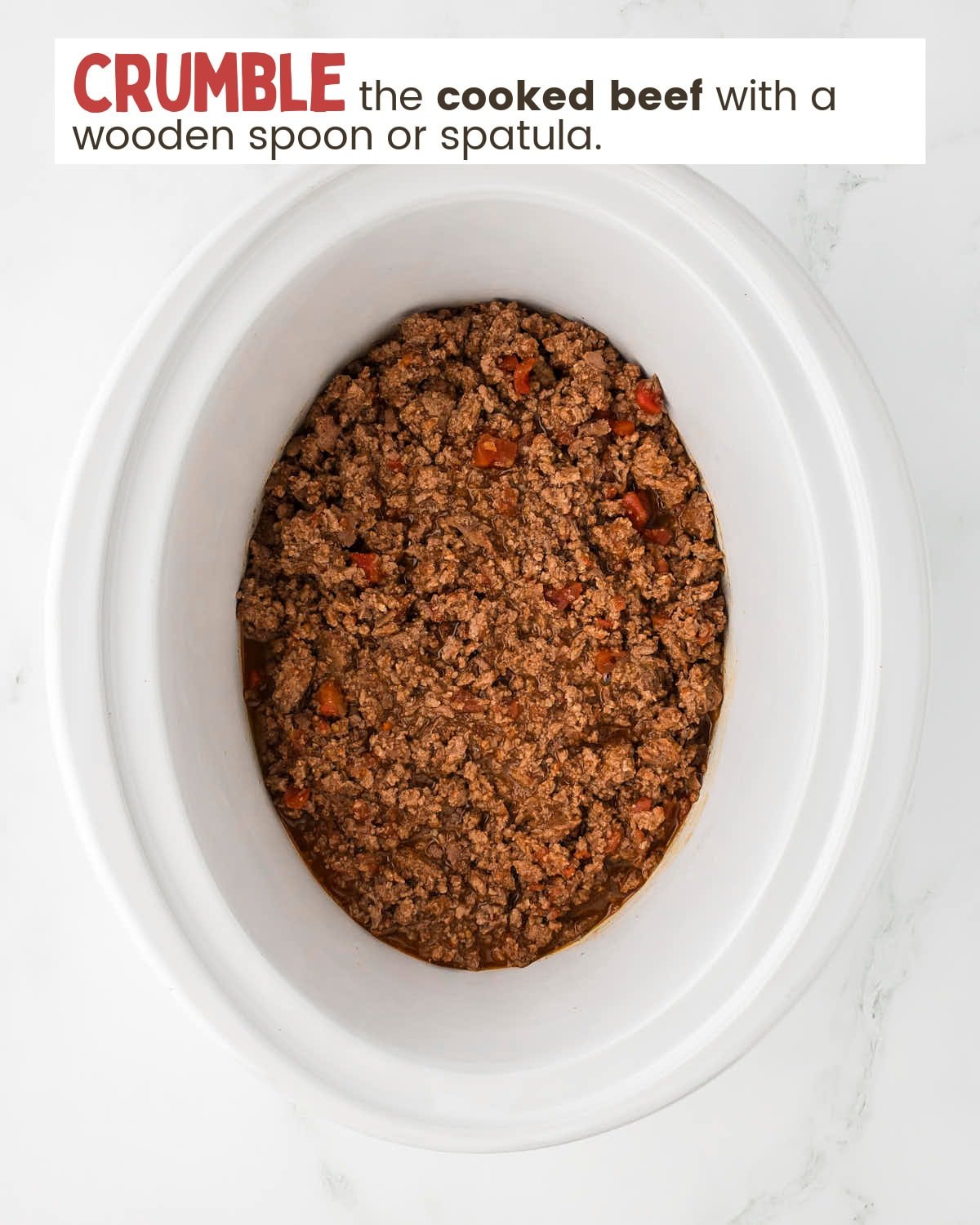 A top-down view of a slow cooker with cooked taco meat.