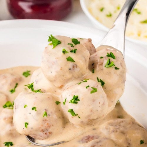 A serving spoon filled with Crockpot Swedish Meatballs.