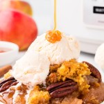 Drizzling slated caramel on a slice of a Crockpot Apple Dump Cake.
